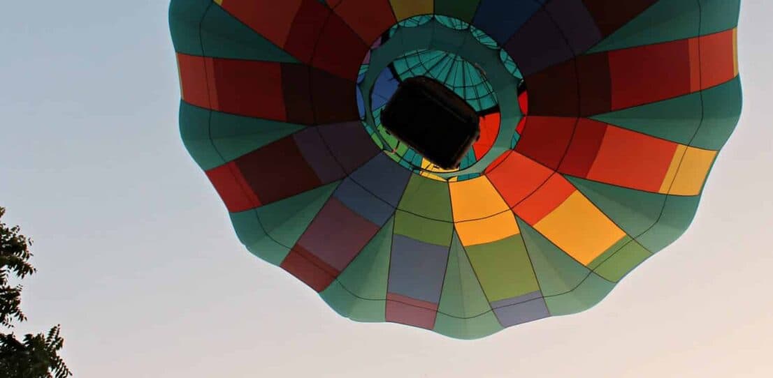 Colorful hot air balloon viewed from below against a clear sky.
