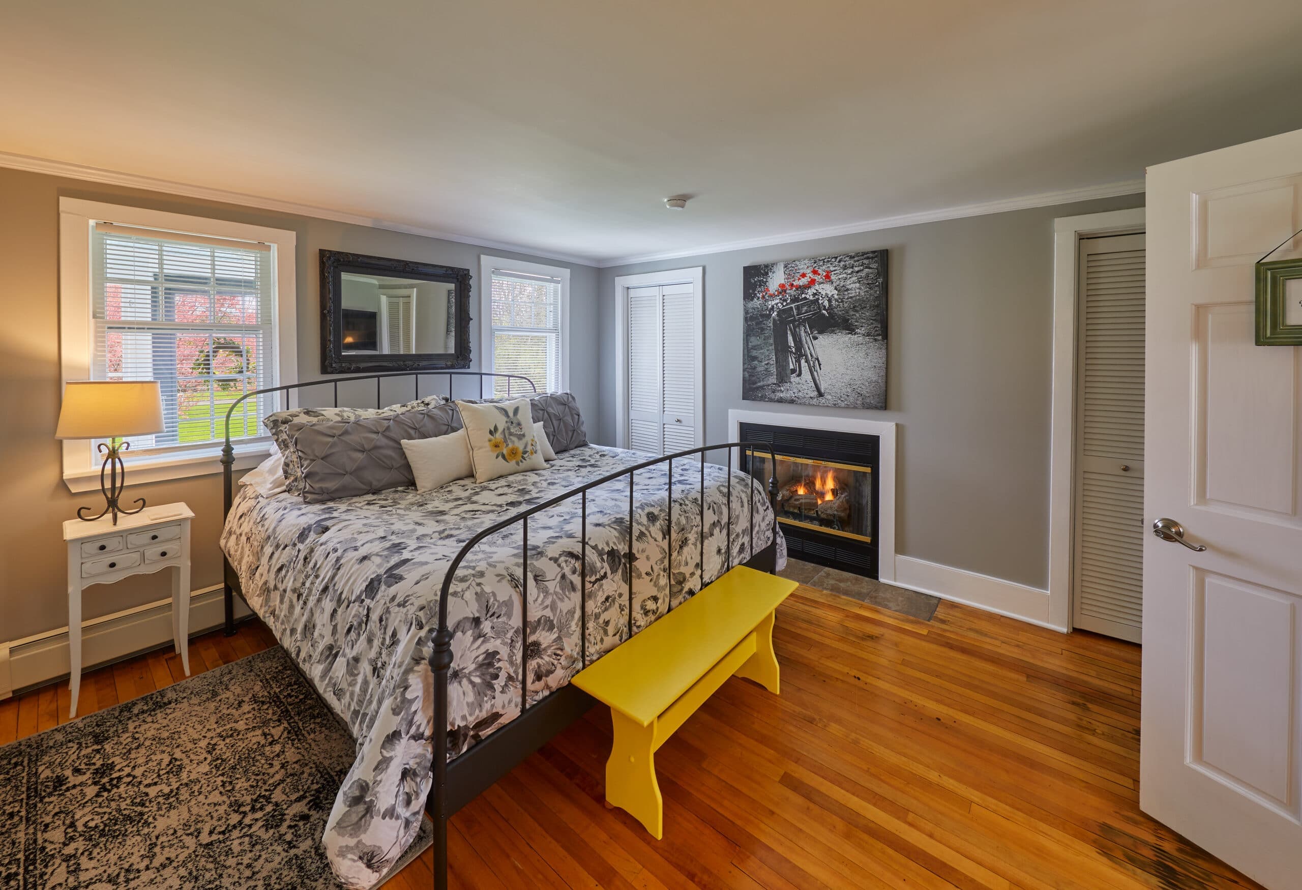 Cozy bedroom featuring a metal bed frame, decorative pillows, a yellow bench, and a fireplace.